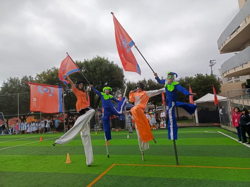 Zanqueros animando evento deportivo escolar con banderines, activación BTL
